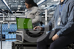 Close up of data center employee using green screen notebook
