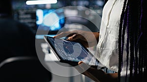 Close up of data center engineer using tablet to review code