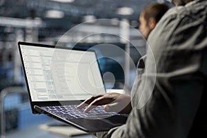 Close up of data center programmer looking at code on laptop
