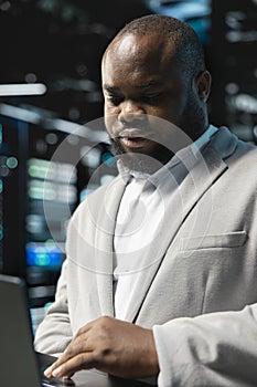 Close up of data center programmer using laptop to protect servers