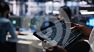 Close up of data center software developer using tablet to review code