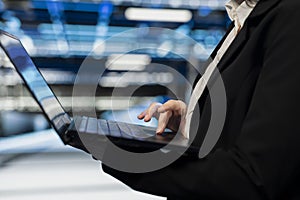 Close up of data center worker using laptop to do maintenance on electronics