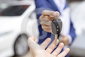 Close up of dealer giving key to new owner and shaking hands in auto show