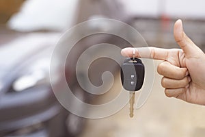 Close up of dealer giving key to new owner and shaking hands in auto show