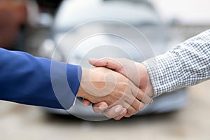 Close up of dealer giving key to new owner and shaking hands in auto show