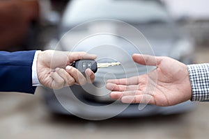 Close up of dealer giving key to new owner and shaking hands in auto show