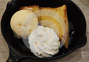 Close-up decorated shaped Bread Toast with whip cream, honey syrup and Vanilla sweet Ice Cream on black ceramic plate