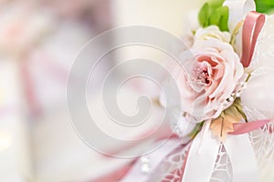 A decorazione made up of a pink rose and a white and pink ribbon photo