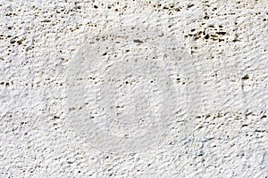 Close-up Deep texture of white-painted porous stone on the facade of the building. Stoned wall background texture