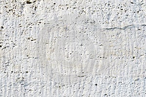 Close-up Deep texture of white-painted porous stone on the facade of the building. Stoned wall background texture