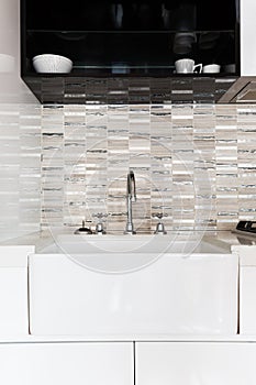 Close up of a deep white kitchen sink and tiled splashback photo