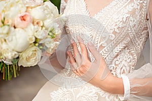 Close-up of a delicate ring on the bride`s hand with pale pink nails.