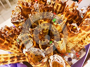 Close-up of delicious chocolate waffle rolls lie on white plate. Preparation of a sweet dessert. White clean kitchen and table.