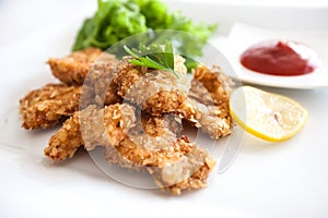 Close-up of delicious crispy fried chicken breast strips on white plate, Chicken nuggets with cornflakes salad and