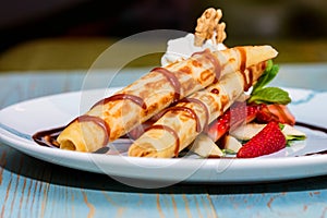 Close up delicious dessert with waffle rolls, ice cream and strawberries