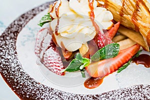 Close up delicious dessert with waffle rolls, ice cream and strawberries
