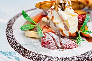 Close up delicious dessert with waffle rolls, ice cream and strawberries