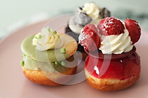 A close up of delicious donuts of strawberry, pistachio and cookie tastes