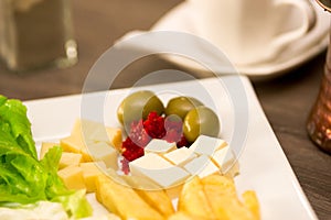 Close up of a delicious fresh mediterranean luch with lettuce, cheesse, fried potato and somes olives on a wooden table