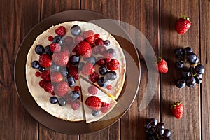 Close up. Delicious Homemade creamy New York Cheesecake with berries on dark wooden table. Top viev.