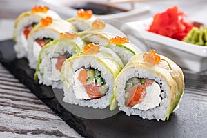 Close up of delicious pieces of sushi covered with fresh slices of avocado and red caviar.