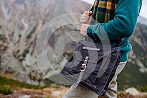 Man weraring crossody bag during the hike in an autumn mountains.