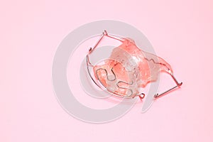 Close up Dental braces orthodontic appliance dental for improving bite gap isolated on pink background, copy space.