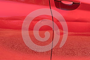 Close-up of dented red car door