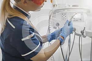 Close up of dentist in blue uniform checking dental equipment and instruments