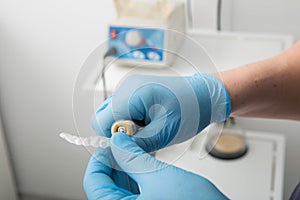 Close up on dentist hands covered with latex gloves shaping mouth guard with file equipment