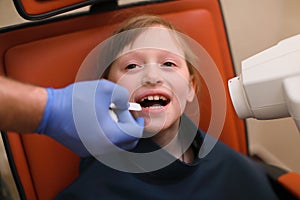 Close up of dentist putting intraoral shield to children patient mouth and assistant directing x-ray machine at dental clinic