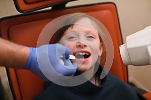 Close up of dentist putting intraoral shield to children patient mouth and assistant directing x-ray machine at dental clinic