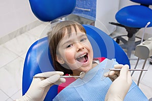 A close-up of a dentistÃ¢â¬â¢s hands and a child with an opened mouth photo