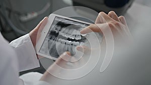 Close-up dentists looking at x-ray on tablet