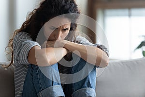 Close up depressed young woman sitting alone, thinking about problems