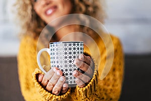 Close up of design trendy mug with tea or coffee or heahty drink holded by adult caucasian woman hands -  cheerful blonde female