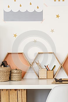 Close-up of a desk with pen cups, shelves in the shape of honeycombs and star stickers on the wall