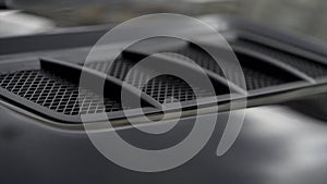 Close up for detail of air vents on the bonnet of a modern black car. Stock. Car exterior background detail of air