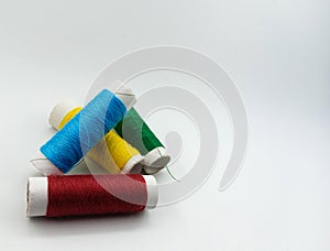 Close up detail of blue yellow red and green reels of thread isolated on white background.