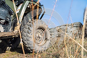 Close-up detail bottom POV view 4x4 awd ATV vehicle on dirt gravel unpaved road in autumn at misty mountain top. Offroad