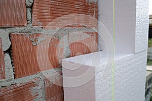 Close-up detail of brick house wall with rigid styrofoam insulation sheet. Modern technology of construction, renovation and