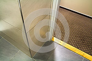 Close-up detail, corner of modern luxurious empty bathroom with floor to ceiling marble ceramic light beige shiny tiles. Professio