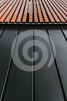 close up detail of dark grey alucobond cladding on the roof, wood slats behind it, contemporary architecture