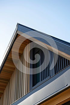 close up detail of dark grey alucobond cladding on the roof, wood slats behind it, contemporary architecture