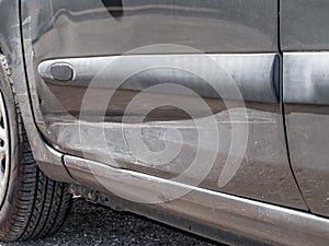 Close up detail of a dented driver door from a car crash or automobile accident.