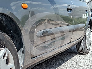 Close up detail of a dented driver door from a car crash or automobile accident.