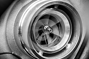 Close up detail of a diesel engine turbocharger with fan blades and center axle - selective focus on center axle