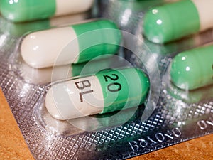 close up detail of foil packet of green and white prozac painkiller tablets on table surface