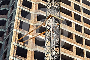 Close-up detail of highrise tower crane attached to building brick wall at hightower industrial construction site