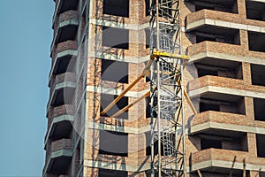 Close-up detail of highrise tower crane attached to building brick wall at hightower industrial construction site. Engineering and